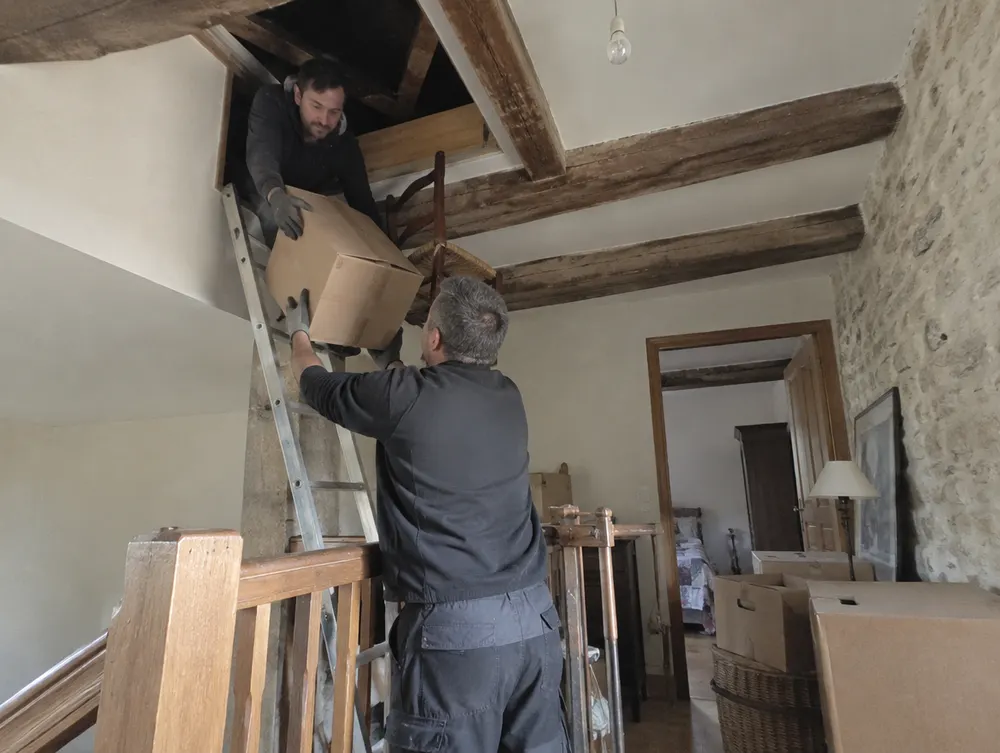 Cartons descendus d'un grenier sous charpente